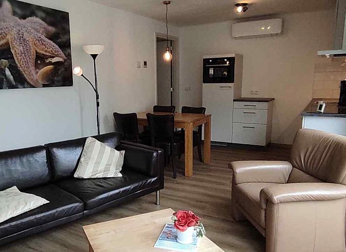 Gemuetliches Wohnzimmer des NH213 Ferienhauses in Callantsoog, Nordholland, mit bequemen Sofas und Essecke.