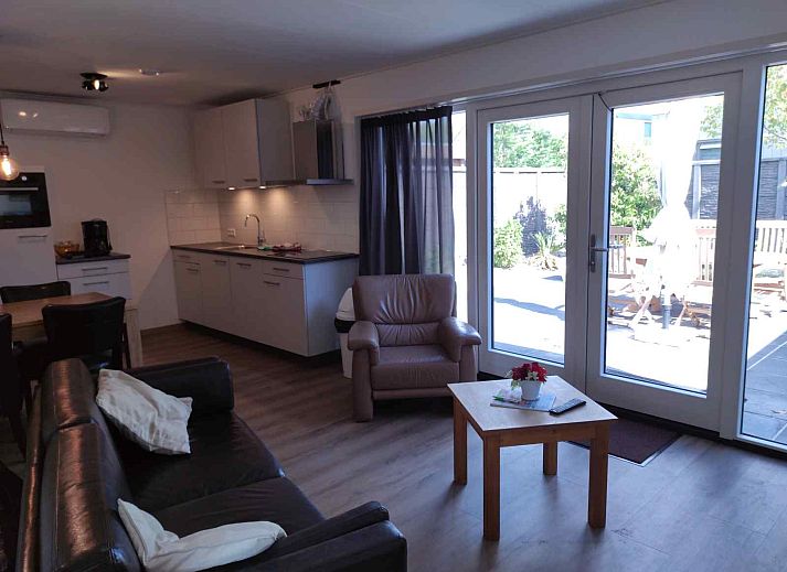 Gemuetliches Wohnzimmer des NH213 Ferienhauses in Callantsoog, Nordholland, mit bequemen Sofas und Essecke.