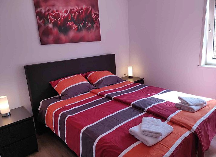 Gemuetliches Wohnzimmer des NH213 Ferienhauses in Callantsoog, Nordholland, mit bequemen Sofas und Essecke.