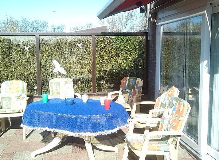 Lichte zithoek in De Blenck 69, een vakantiehuis aan de Noordzeekust, met ruime bank en uitzicht op de tuin.