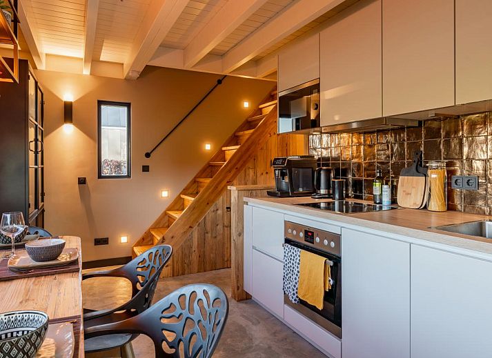 Gemuetliches Wohnzimmer von Spoelde wiel in Callantsoog mit Kamin und modernen Moebeln.