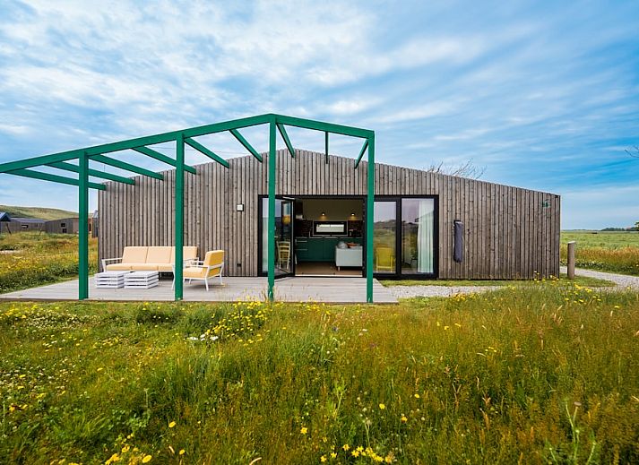 Aussenansicht des Ferienhauses Royal Dune 4 in Callantsoog mit grosser Veranda und natuerlicher Umgebung.
