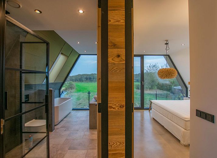 Innenraum des Ferienhauses De Bonte Specht in Callantsoog mit Holzinterieur und grossen Fenstern.