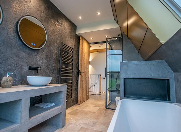 Innenraum des Ferienhauses De Bonte Specht in Callantsoog mit Holzinterieur und grossen Fenstern.