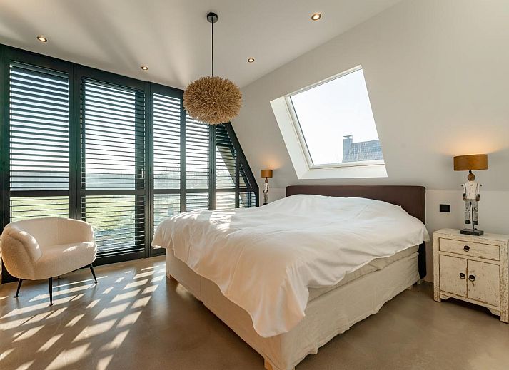 Innenraum des Ferienhauses De Bonte Specht in Callantsoog mit Holzinterieur und grossen Fenstern.