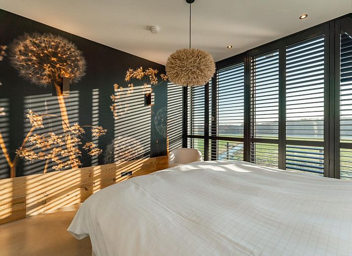 Gemuetliche Sitzecke im Ferienhaus De Bonte Specht, Callantsoog, mit Steinwand und Kaminofen.