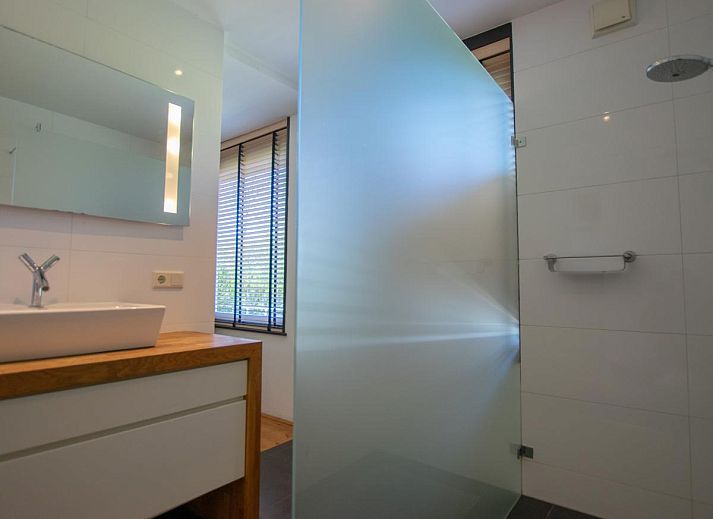 Gezellige woonkamer van Landhuis Duinzicht in Callantsoog, Noord-Holland met uitzicht op de groene tuin aan de Noordzeekust.