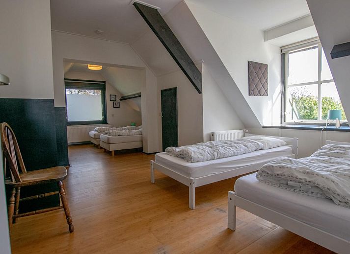 Gezellige woonkamer van Landhuis Duinzicht in Callantsoog, Noord-Holland met uitzicht op de groene tuin aan de Noordzeekust.