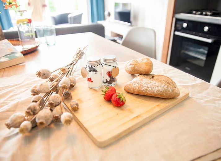 Esstisch im Ferienhaus in Callantsoog, Nordseekueste, Nordholland, mit frischem Brot und Blumen.
