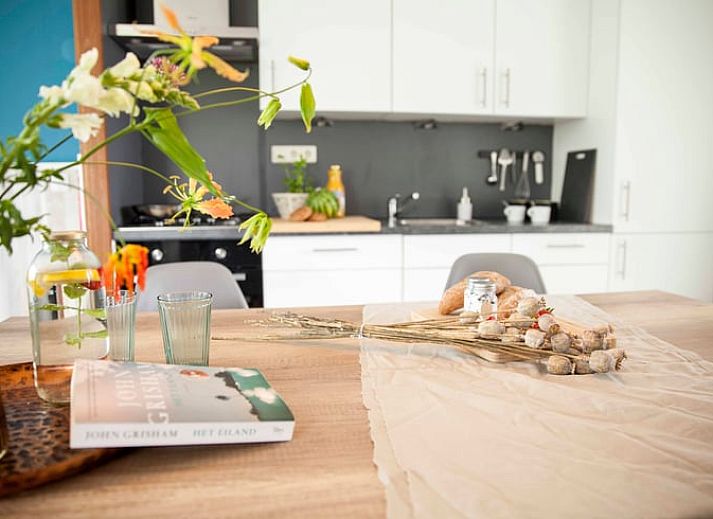 Esstisch im Ferienhaus in Callantsoog, Nordseekueste, Nordholland, mit frischem Brot und Blumen.