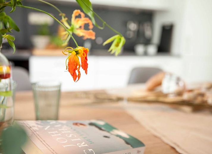 Esstisch im Ferienhaus in Callantsoog, Nordseekueste, Nordholland, mit frischem Brot und Blumen.