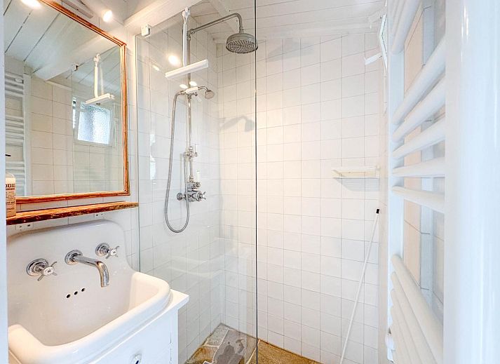 Lichte woonkamer van vakantiehuis Sol in Callantsoog met uitzicht op de tuin.