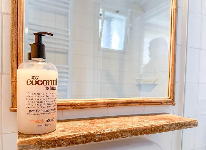 Lichte woonkamer van vakantiehuis Sol in Callantsoog met uitzicht op de tuin.