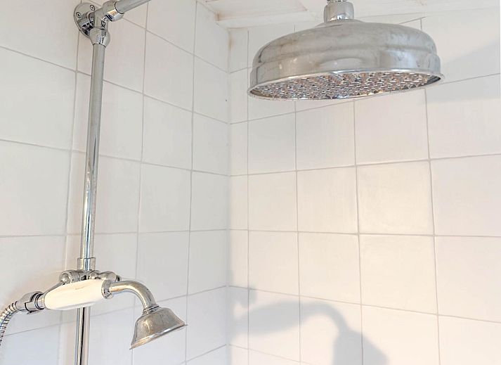 Lichte woonkamer van vakantiehuis Sol in Callantsoog met uitzicht op de tuin.