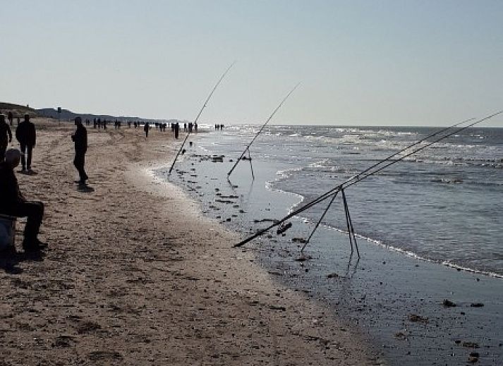 Eetkamer in vakantiehuis Rekere 111, Schoorldam, Noordzeekust, Noord-Holland met houten tafel en sfeervolle verlichting.