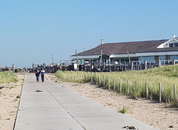 Eetkamer in vakantiehuis Rekere 111, Schoorldam, Noordzeekust, Noord-Holland met houten tafel en sfeervolle verlichting.
