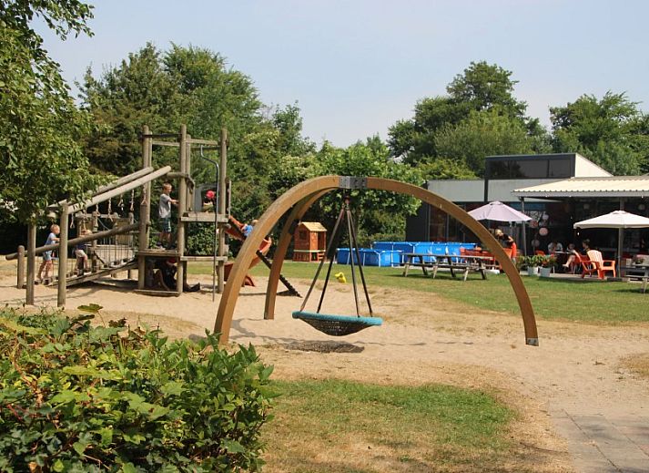 Eetkamer in vakantiehuis Rekere 111, Schoorldam, Noordzeekust, Noord-Holland met houten tafel en sfeervolle verlichting.