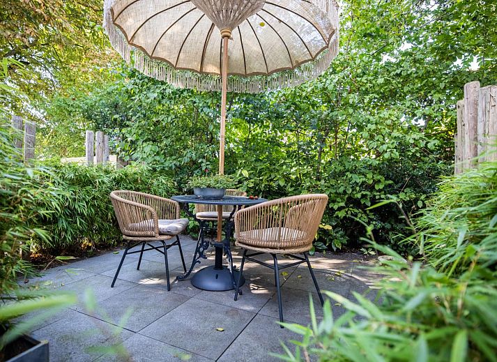 Geniet van de serene tuinveranda bij De Egelhut, een vakantiehuis aan de Noordzeekust in Bergen, Noord-Holland.