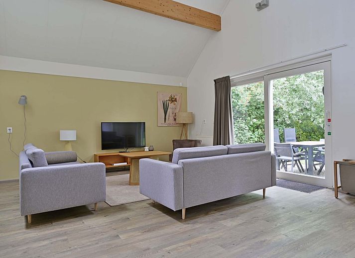 Terras van vakantiehuis in Julianadorp aan Zee met tuinmeubilair en parasol.
