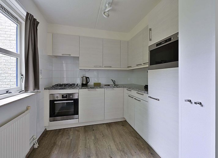 Terras van vakantiehuis in Julianadorp aan Zee met tuinmeubilair en parasol.