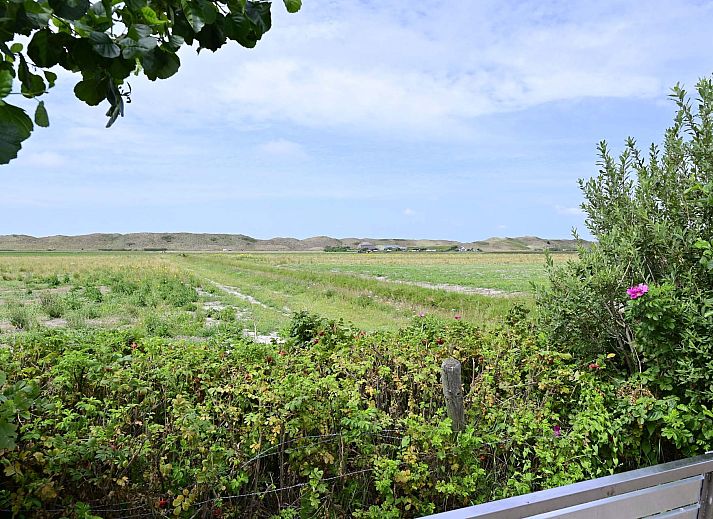 Woonkamer met schuifpui naar tuin in vakantiewoning Julianadorp aan Zee, Noord-Holland.