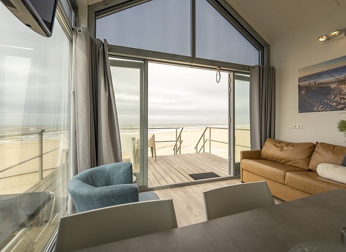 Geniet van het uitzicht op zee vanuit de lichte woonkamer van Beach House Comfort 4, een vakantiehuis in Julianadorp aan Zee, Noord-Holland.