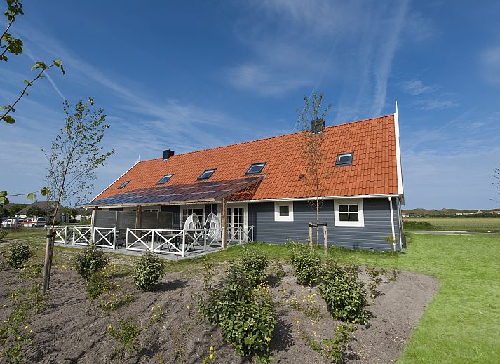 Beach Resort Ooghduyne 16-persoons villa in Julianadorp aan Zee, charmant exterieur met rode dakpannen en groene tuin.