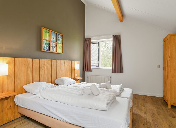 Comfortabele slaapkamer in Beach Resort Ooghduyne villa, Julianadorp aan Zee, met houten accenten.