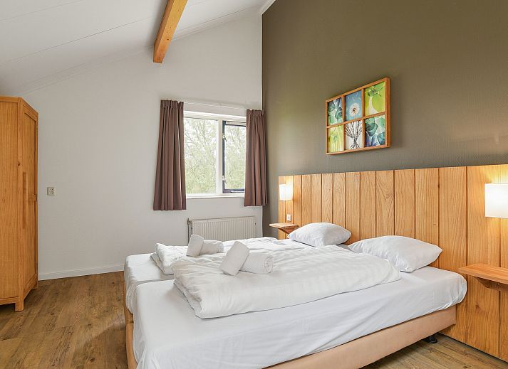 Comfortabele slaapkamer in Beach Resort Ooghduyne villa, Julianadorp aan Zee, met houten accenten.