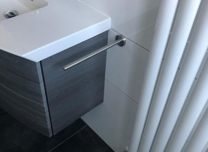 Moderne keuken in Huis op Duynopgangh, Julianadorp, vakantiehuis aan de Noordzeekust, met strakke witte kasten en uitzicht op de tuin.