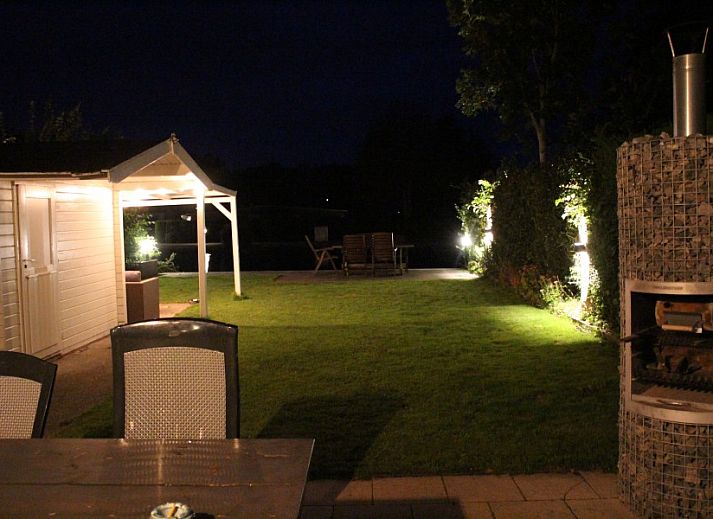 Blick von der ueberdachten Terrasse des Ferienhauses Visvriend in Wervershoof, Nordholland mit Garten und Wasser.