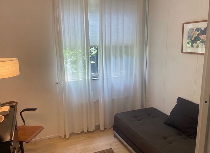 Geraeumiges Wohnzimmer des Ferienhauses in Andijk, IJsselmeerkueste, Nordholland mit bequemer Sitz- und Essecke.