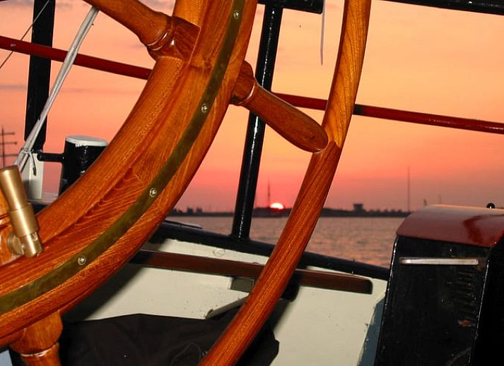 Huisje in Muiden biedt een gezellige binnenruimte met houten interieur en eethoek, ideaal voor een vakantie aan de IJsselmeerkust.