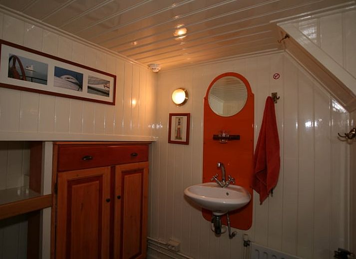 Huisje in Muiden biedt een gezellige binnenruimte met houten interieur en eethoek, ideaal voor een vakantie aan de IJsselmeerkust.