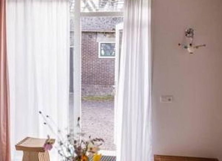 Moderne Kueche im Ferienhaus in Hem, IJsselmeerkueste, Nordholland mit Holztisch und orangefarbener Wand.