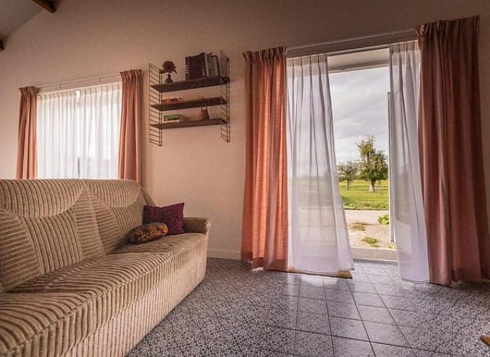 Gemuetliches Wohnzimmer des Ferienhauses in Hem, IJsselmeerkueste mit Holzbalken und orangefarbenen Akzenten.