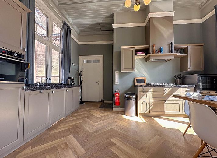 Lichte woonkamer van Groot Weeshuis vakantiehuis in Enkhuizen, Noord-Holland met ruime zithoek en grote ramen met uitzicht op de natuur.