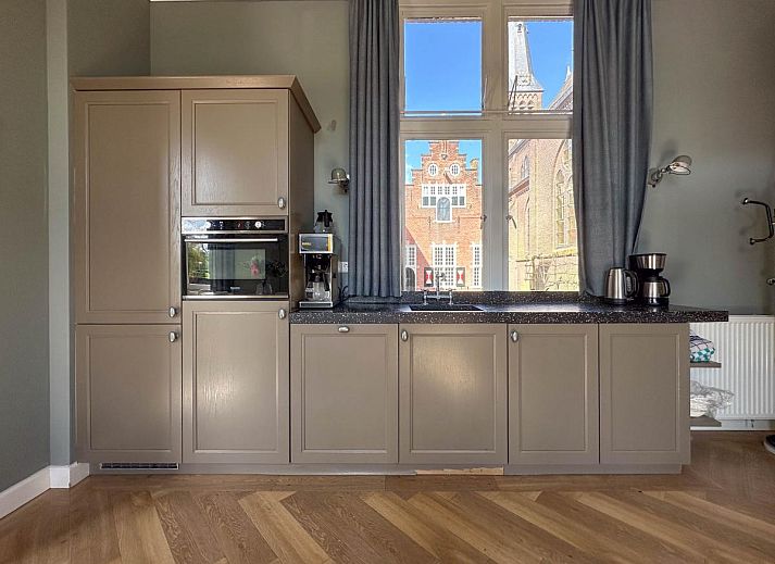 Lichte woonkamer van Groot Weeshuis vakantiehuis in Enkhuizen, Noord-Holland met ruime zithoek en grote ramen met uitzicht op de natuur.