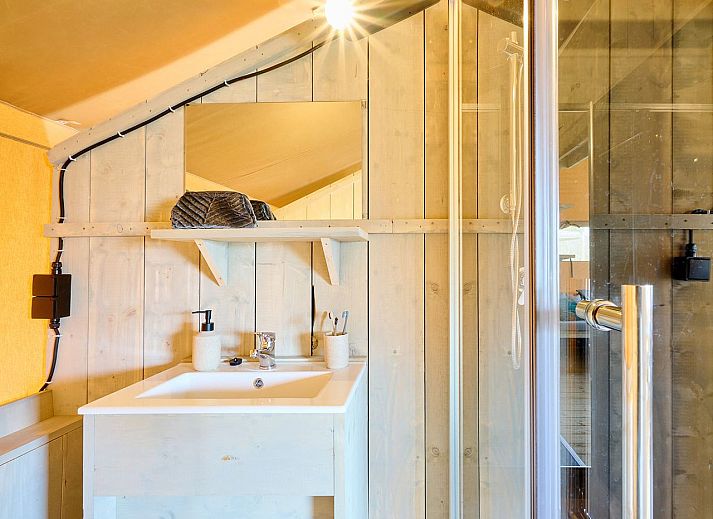 Gezellige binnenruimte van safaritent 6-8ST in Huizen, met eettafel en moderne faciliteiten.