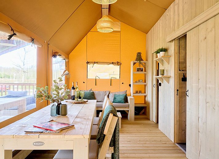 Gezellige binnenruimte van safaritent 6-8ST in Huizen, met eettafel en moderne faciliteiten.