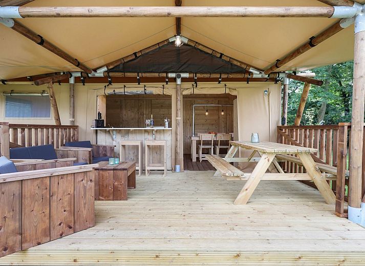 Rustic glamping lodge 4-6S1 in Huizen, North Holland, with wooden terrace and wooded backdrop.
