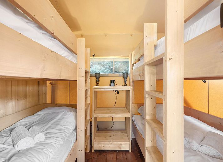 Indoor area of safari tent 4-6S1 in Huizen, North Holland, with comfortable sitting area and view of terrace.