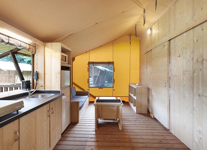 Indoor area of safari tent 4-6S1 in Huizen, North Holland, with comfortable sitting area and view of terrace.