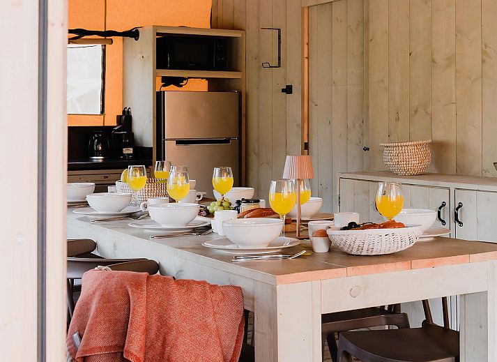 Geniet van een stijlvol gedekte tafel in De Bosvilla, een luxe tenthuis in Huizen, IJsselmeerkust, met uitzicht op de natuurlijke omgeving.
