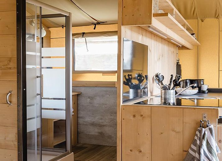 Gezellige binnenruimte van De Bos Escape in Huizen, Noord-Holland met keuken en eetgedeelte, ideaal voor een glamping ervaring.