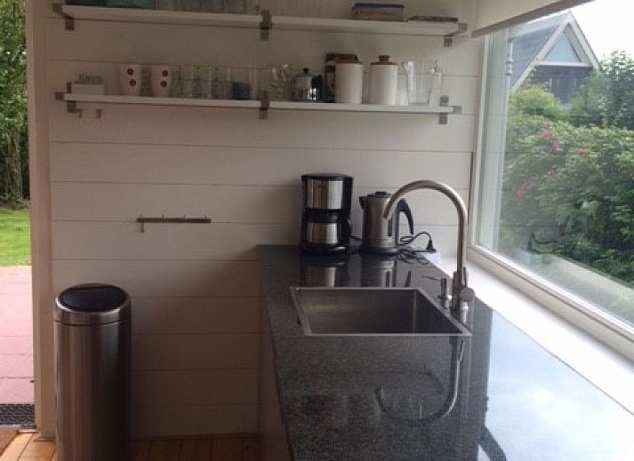 Gezellig terras van strandhuis Sandepark 31 in Callantsoog, Noordzeekust, Noord-Holland, met parasol en tuinmeubilair.