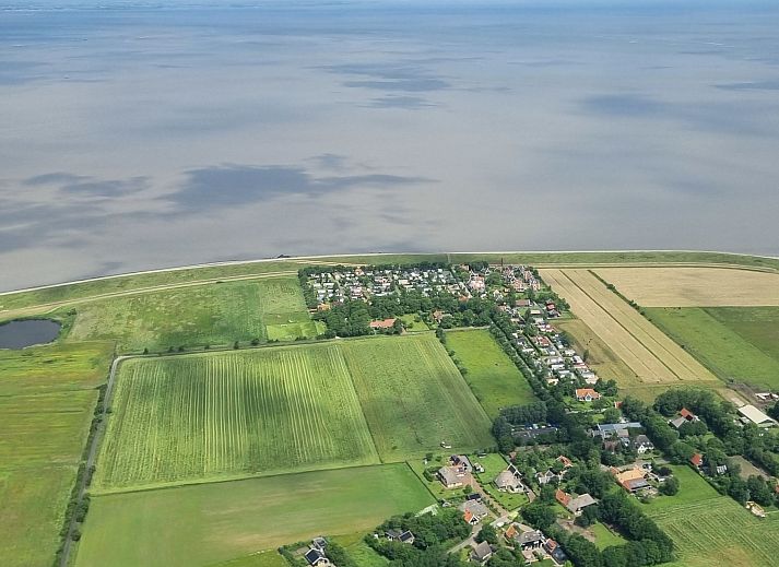 Geraeumiges Wohnzimmer des Ferienhauses Wiringherlant in Wieringen, Nordholland, mit Blick auf den Garten und bequemen Moebeln.