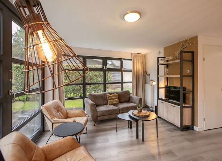 Buitenhuis bungalow in Schoorl, Noord-Holland, met rieten dak en zonnig terras, ideaal voor een ontspannen vakantie in de natuur.