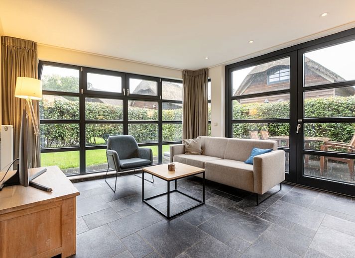 Buitenhuis bungalow in Schoorl, Noord-Holland, met rieten dak en zonnig terras, ideaal voor een ontspannen vakantie in de natuur.