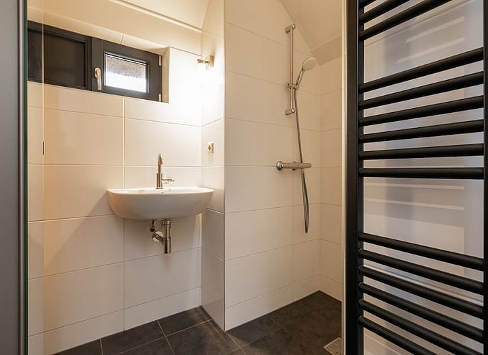 Stijlvolle woonkamer van Buitenhuis bungalow in Schoorl, Noord-Holland. Ruime zitruimte met moderne inrichting en uitzicht op de tuin.